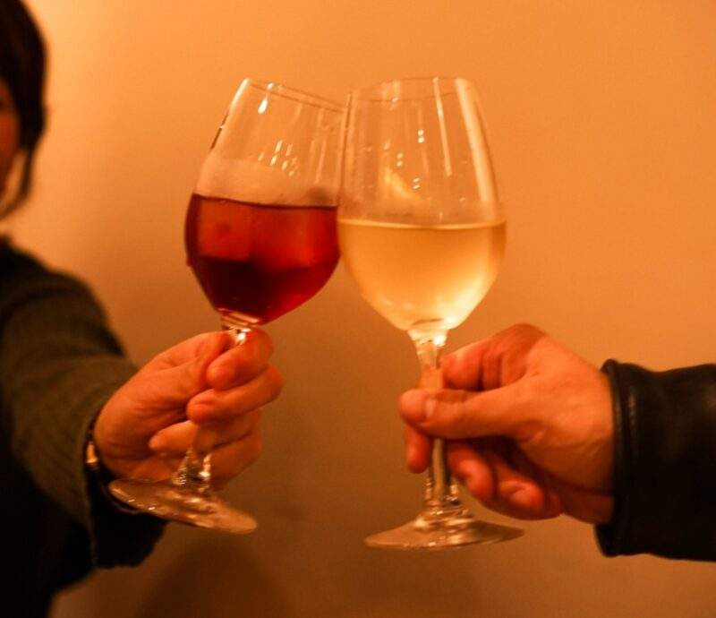 ワイングラスを傾けるカップルの画像